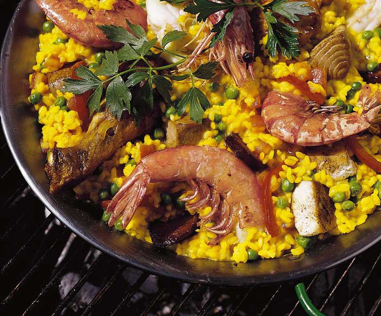Auf dem offenen Feuer im Freien zubereitet und aus der Pfanne gegessen: So liebt man Paella in Spanien.