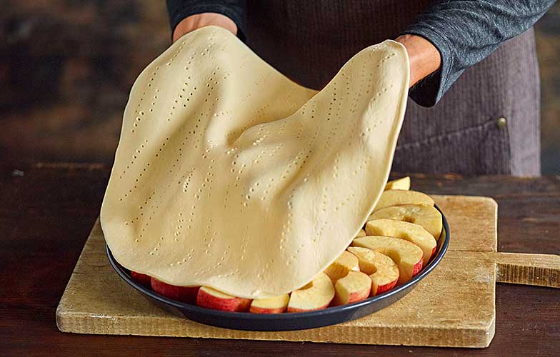 Il faut piquer la pâte généreusement à la fourchette avant de la déposer sur les pommes.